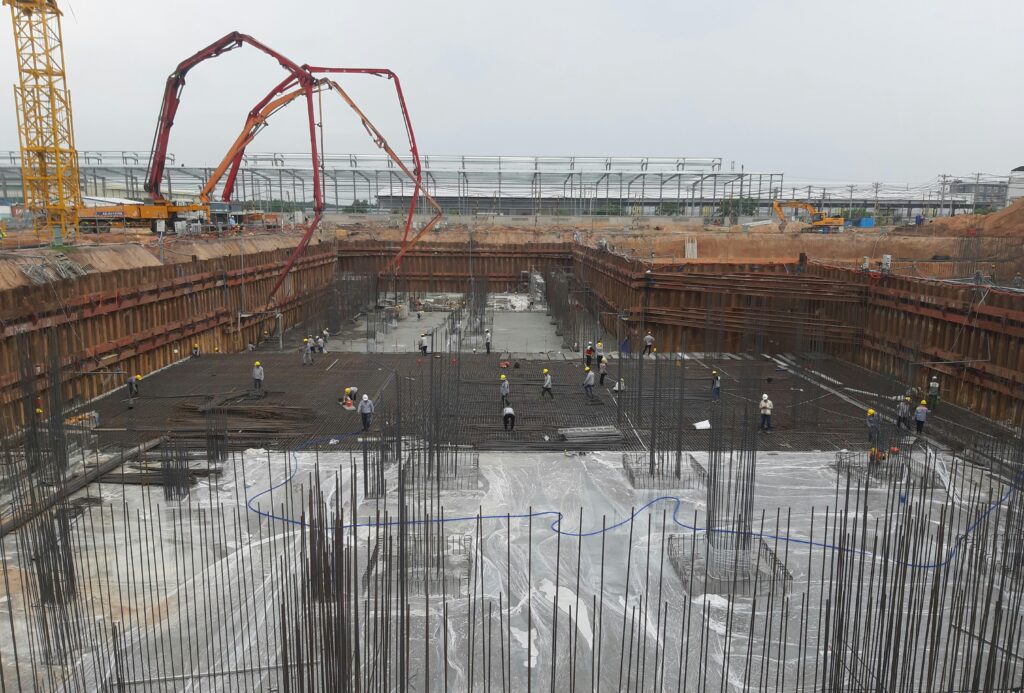 Construction site with workers setting foundation and steel reinforcements.